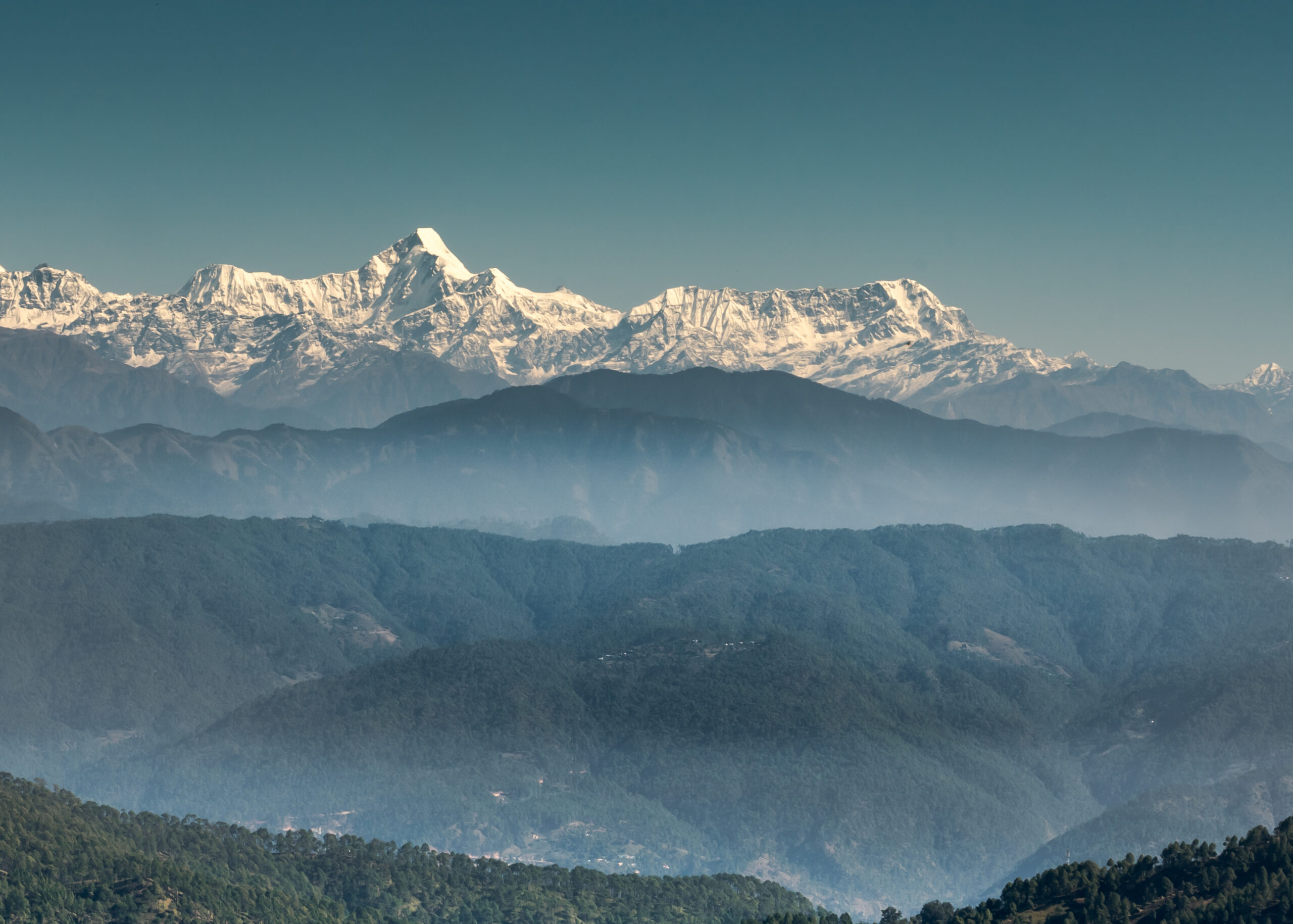 A landscape view of the Himalayan mountain ranges on a clear sky background